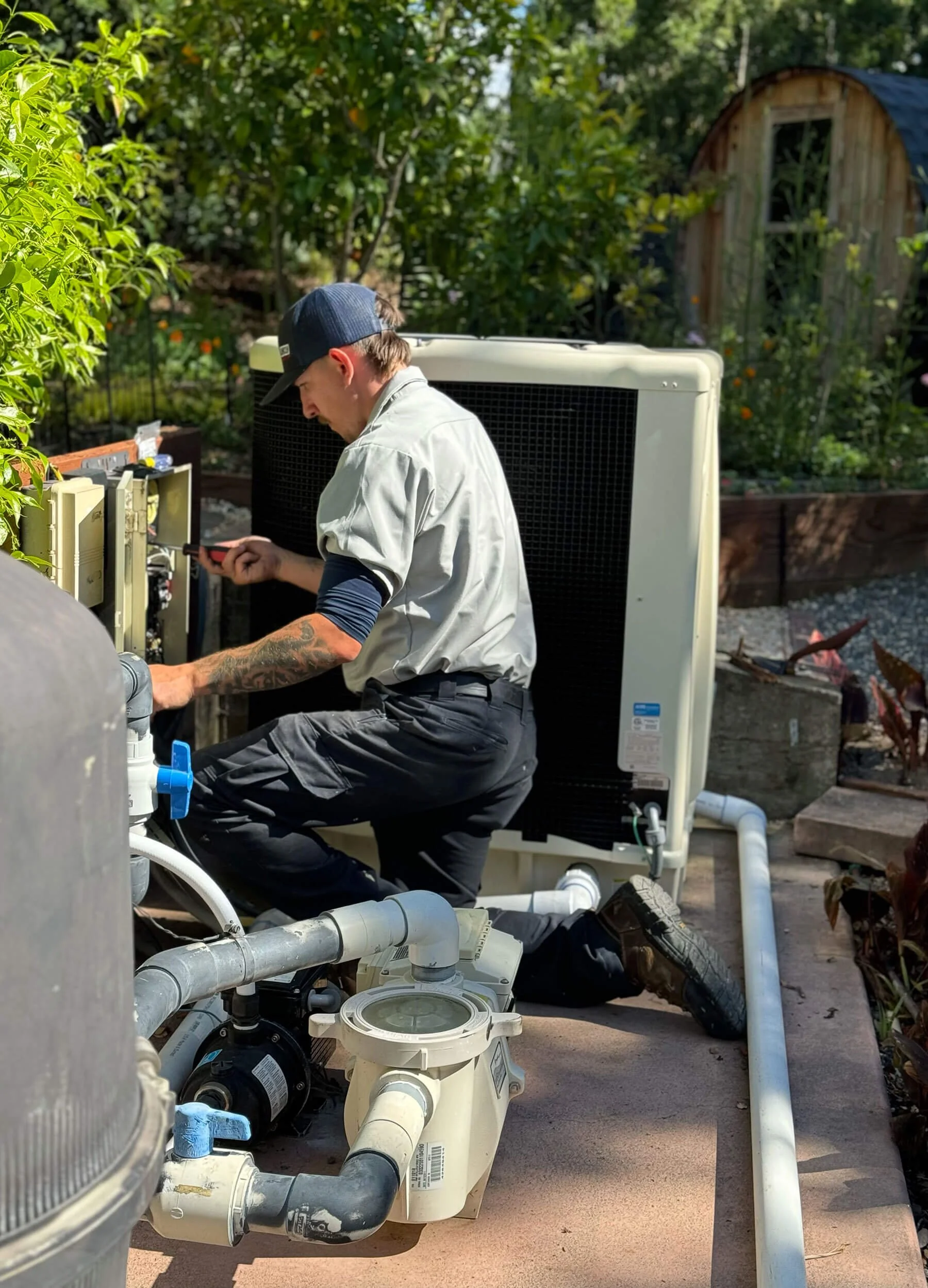 JPS Repair Technician working on pool equipment in a residential backyard setting.
