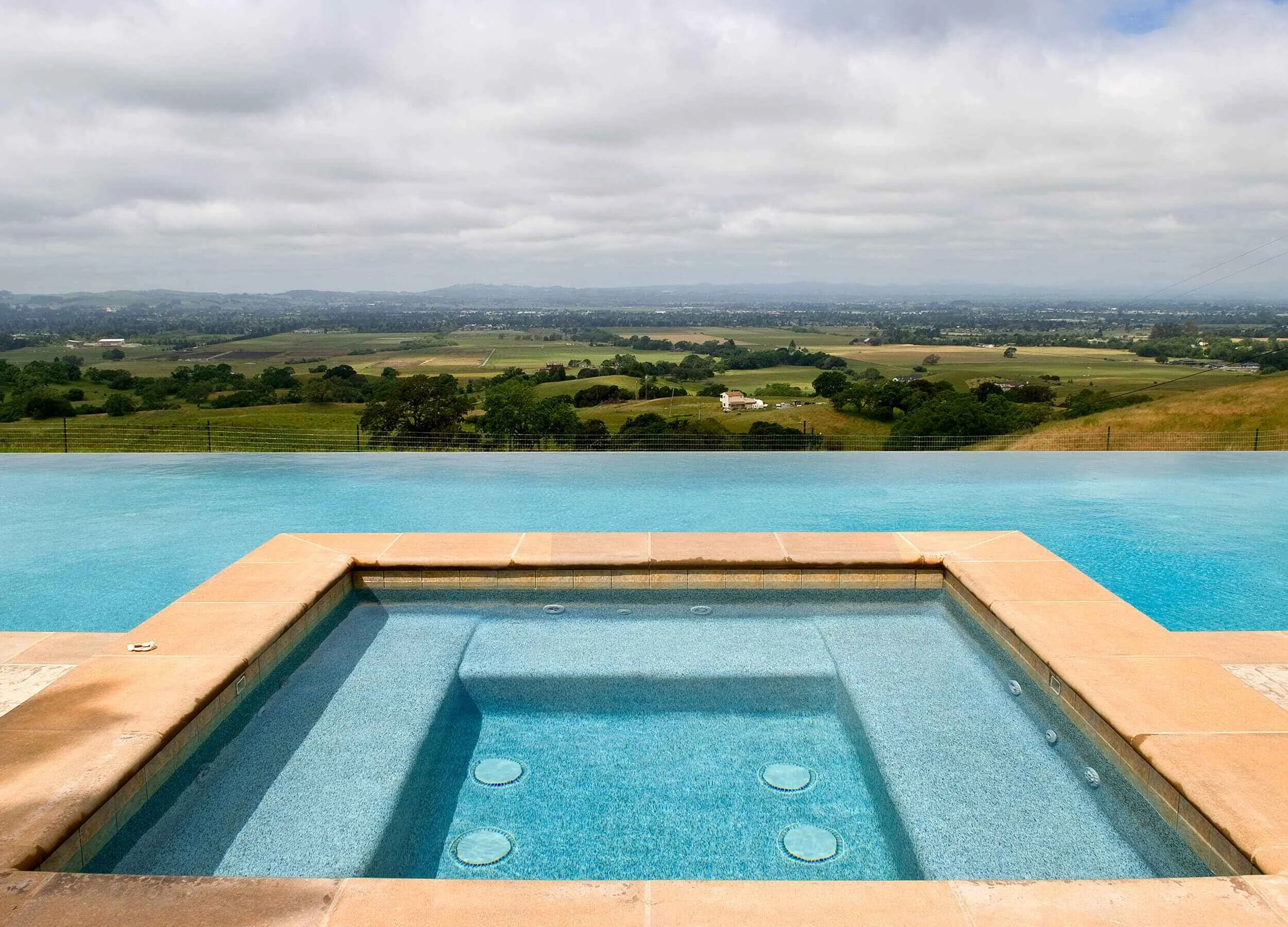 Pastoral view from a client's vanishing ege pool overlooking a valley on a cloudy sky day.