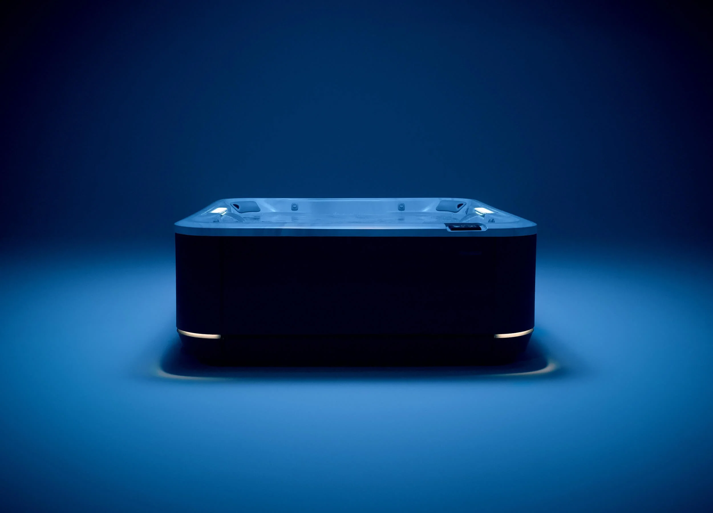 J5095™ Hot Tub on display in an indoor, moody blue-lit setting.