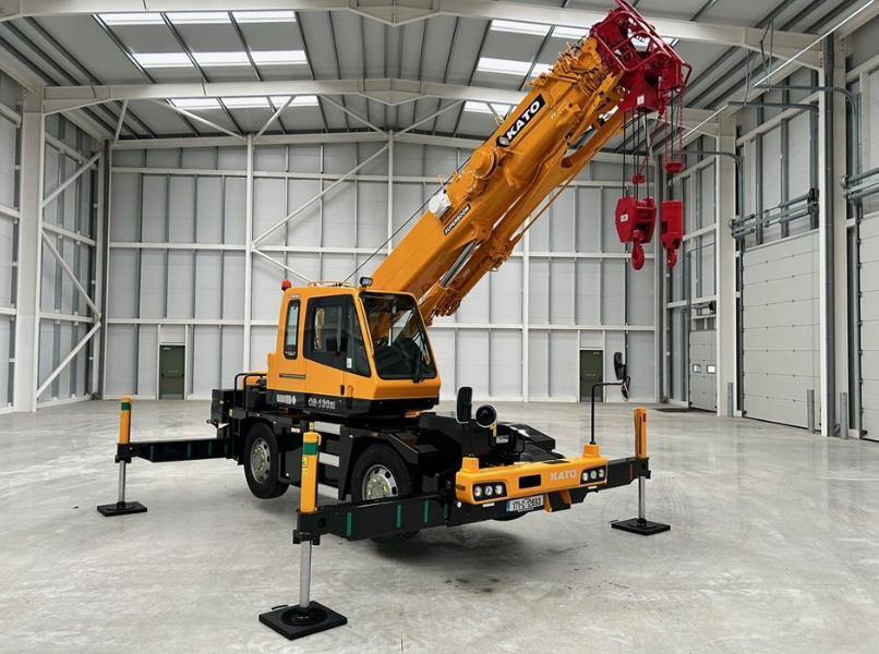 Red mobile crane with outriggers extended on gravel ground