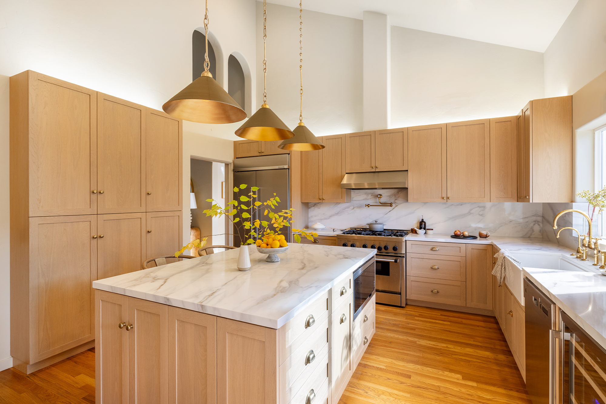 Kitchen with wooden cabinets, marble countertops, gold pendant lights, stainless steel appliances, and a window above the sink.