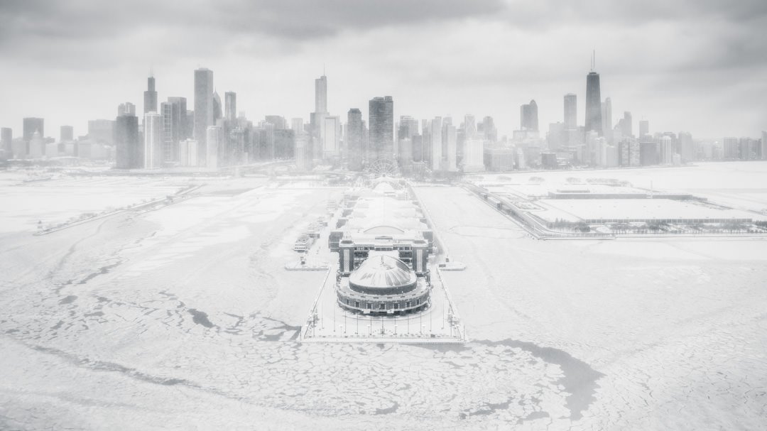 Ethereal winter scene of Chicago with icy Lake Michigan and snow-covered Navy Pier against a misty skyline.