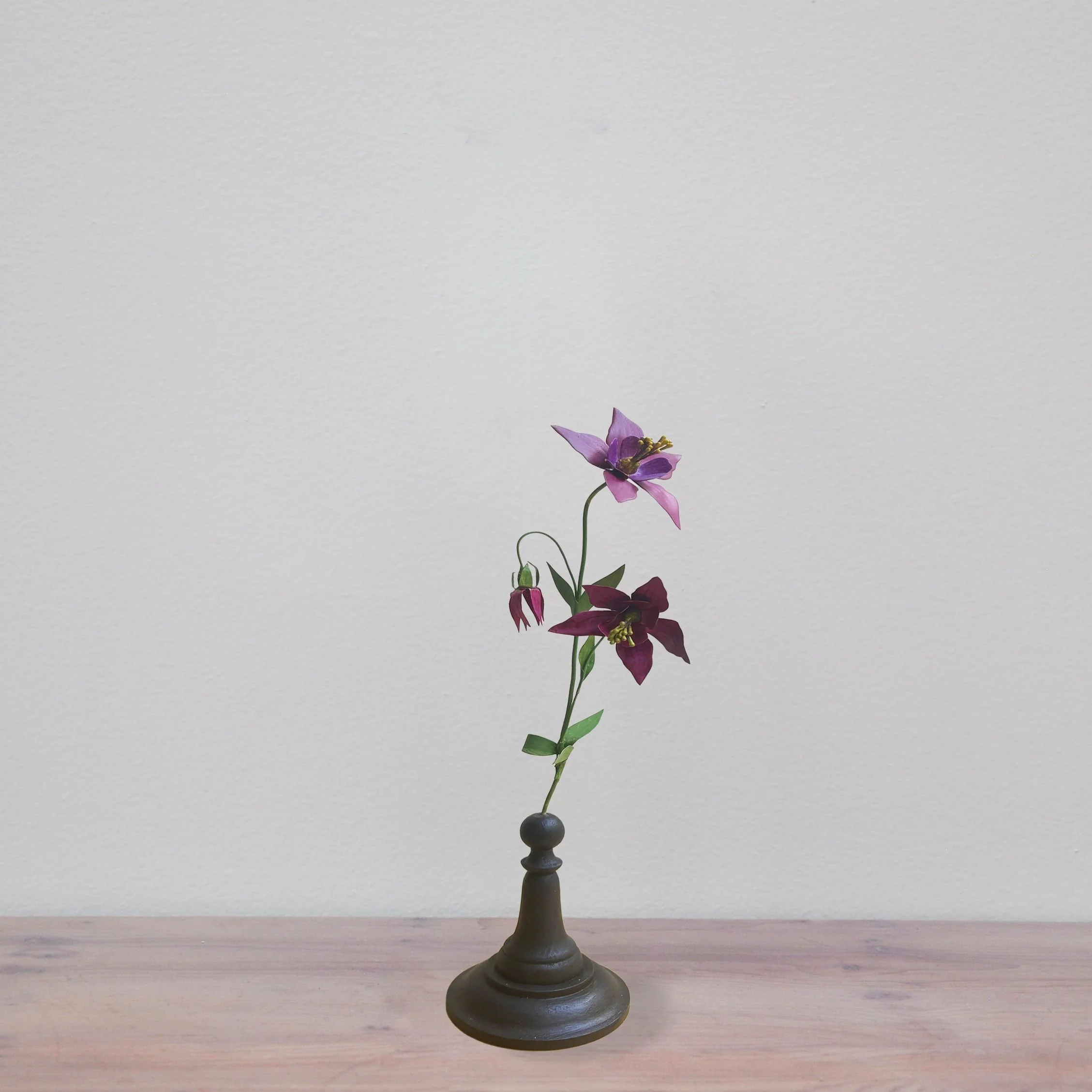 Purple and burgundy flowers in a small black vase