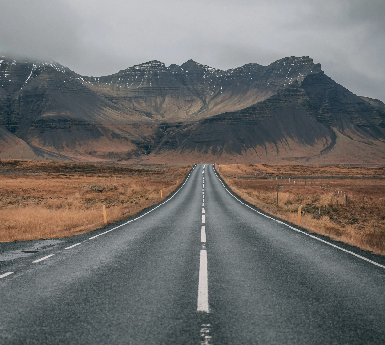 A clear, straight road stretching toward scenic mountains, illustrating the goal-oriented path forward and forward-moving journey of Solution-Focused Brief Therapy.