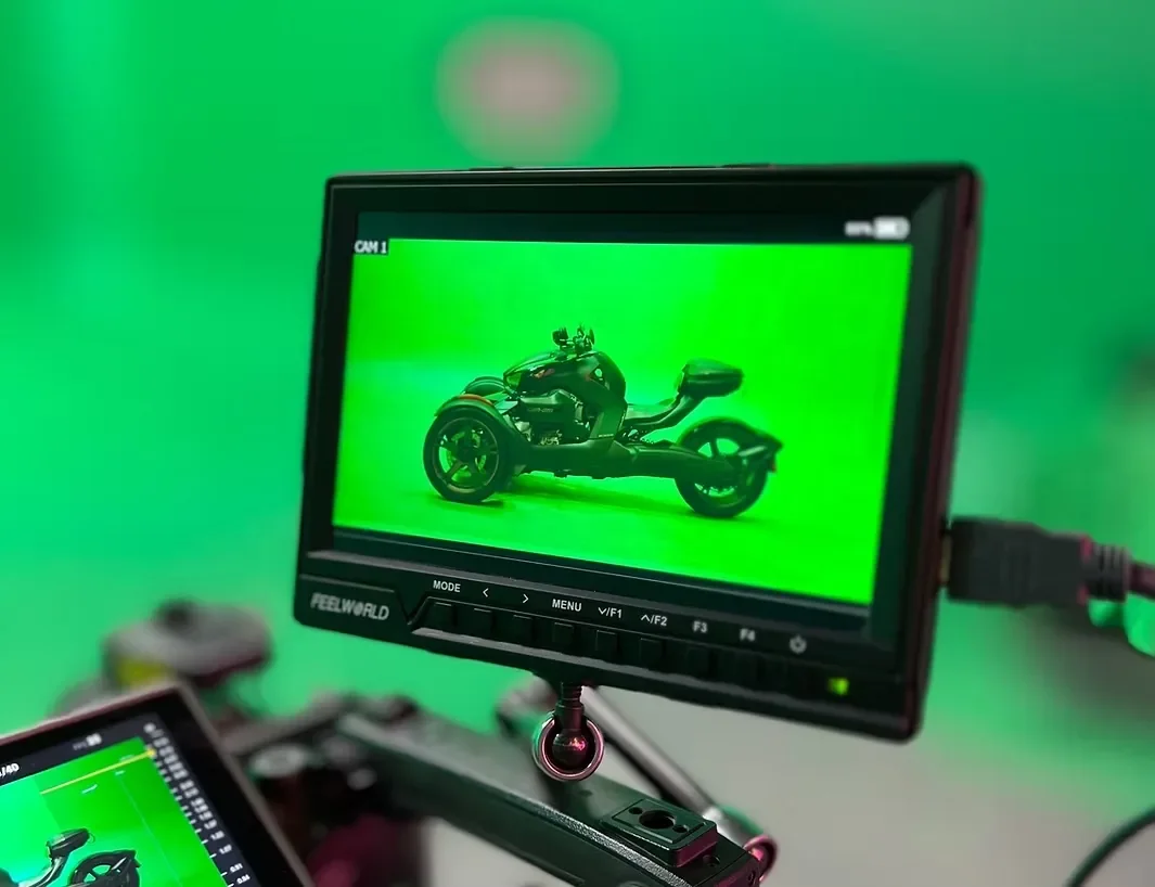 Professional camera monitor displaying a three-wheeled motorcycle against a green screen backdrop during a studio production.