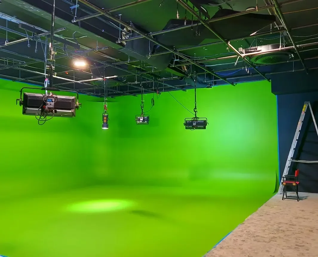 Green screen cyclorama studio with overhead ceiling rigging grid and suspended professional lighting equipment at Jersey Victory Studios.