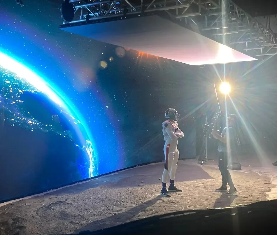 Behind-the-scenes filming on a virtual production LED stage featuring an astronaut, space background, and professional lighting equipment.