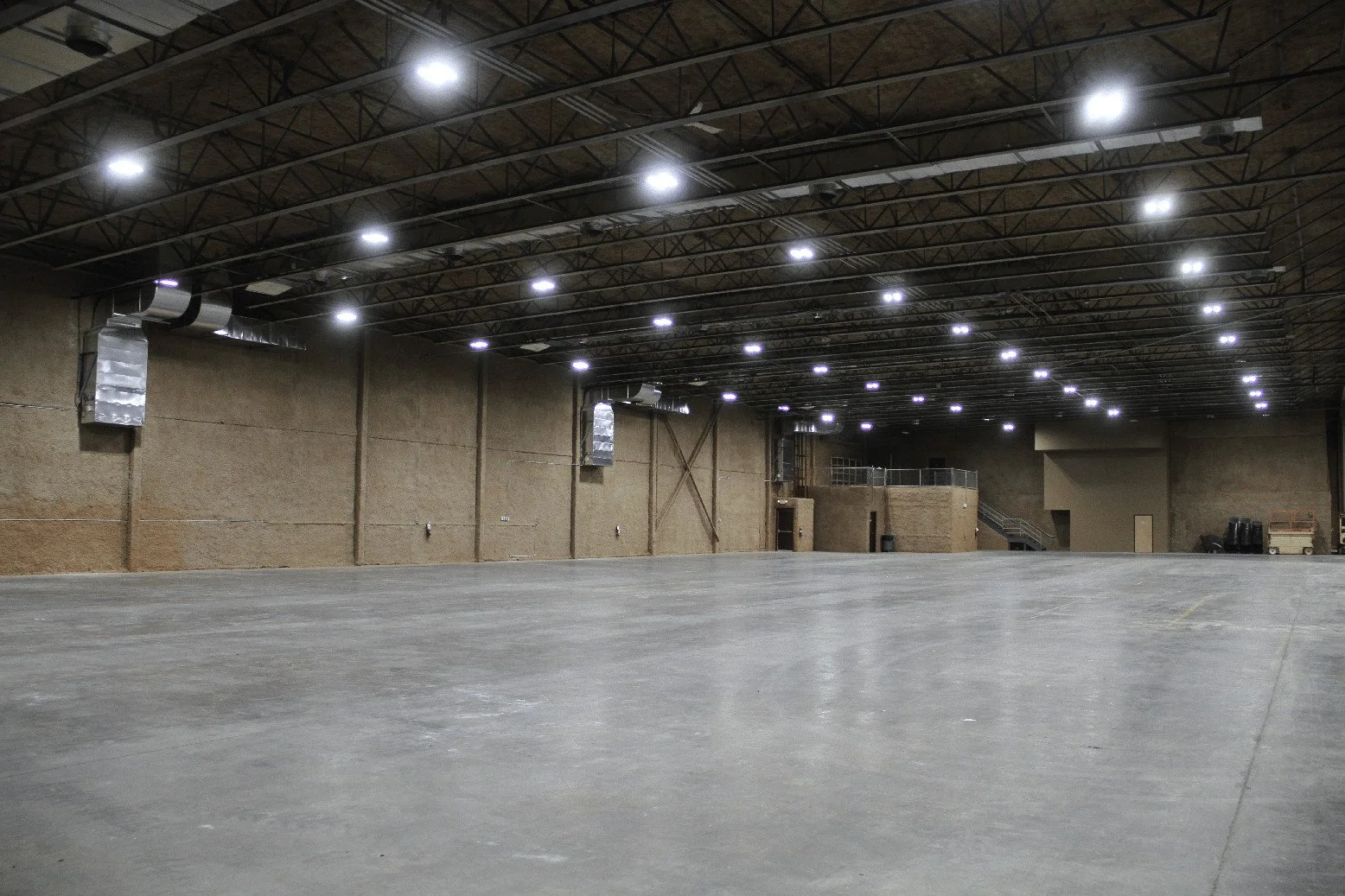 A large empty studio with high ceilings, bright lights, and polished concrete floors, ideal for production or events.
