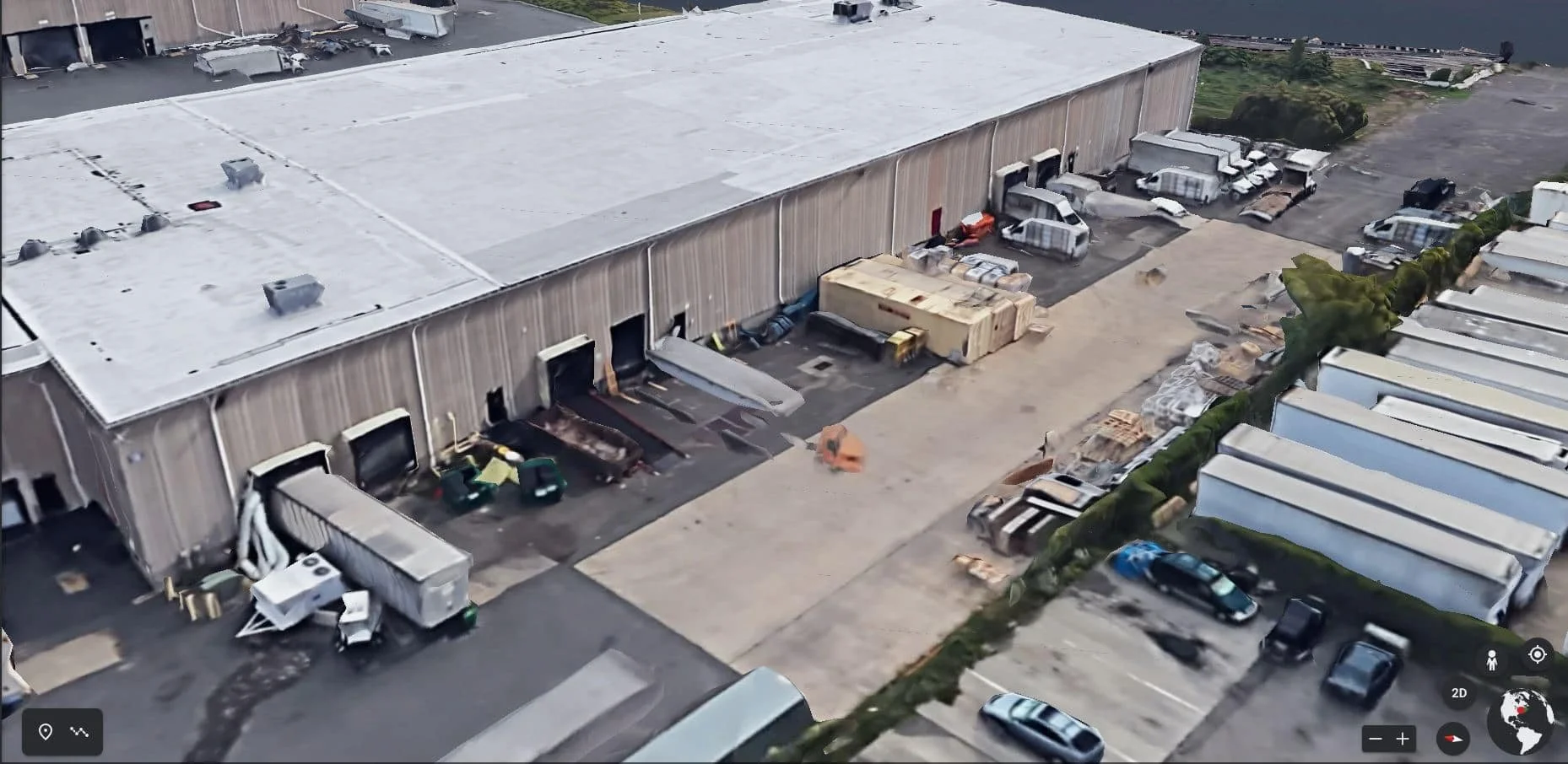 An aerial view of a warehouse with loading docks, trucks, and storage areas, suitable for production or logistics.