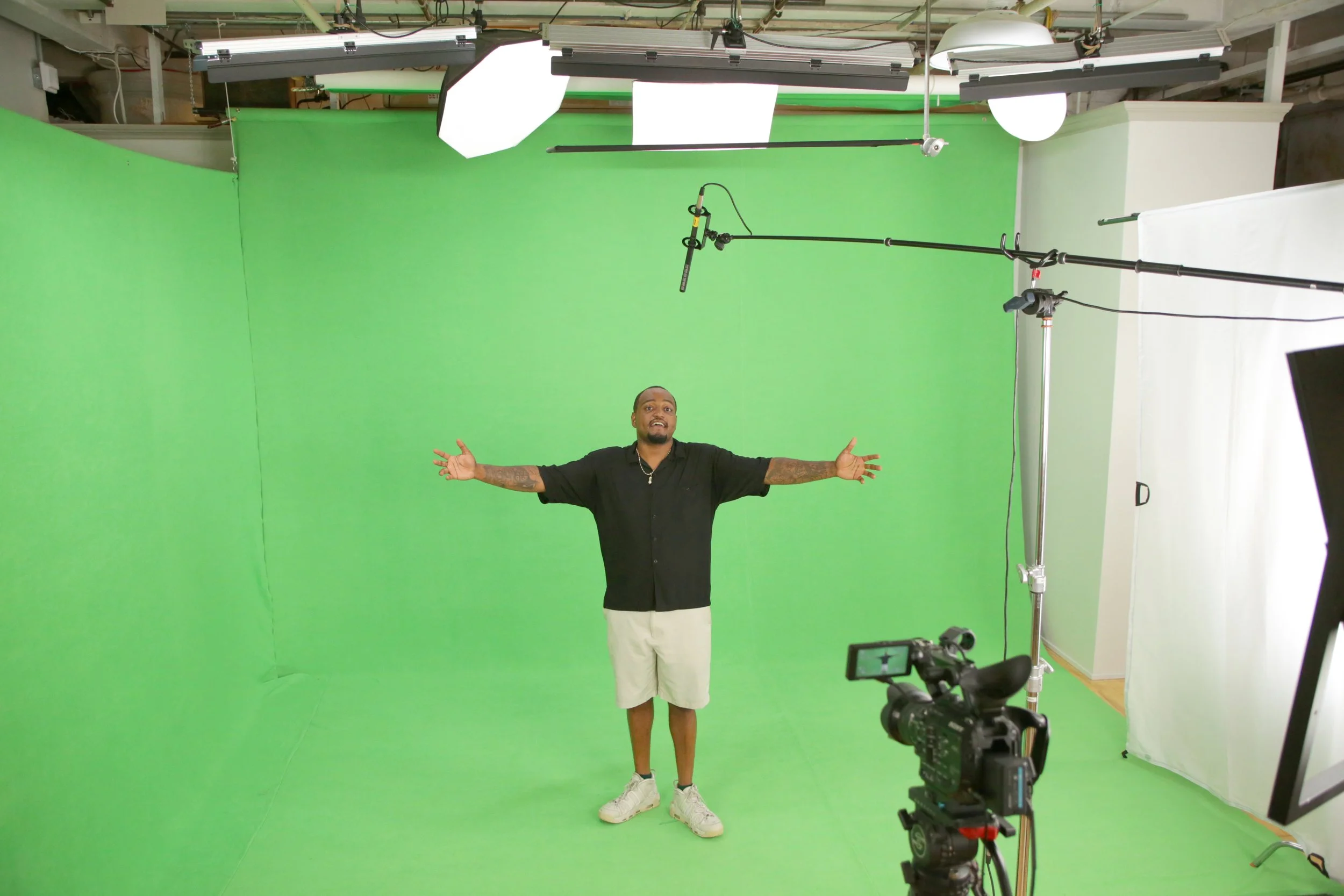 A pro film setup with a cinema camera, lighting, and teleprompter aimed at an interview subject indoors.