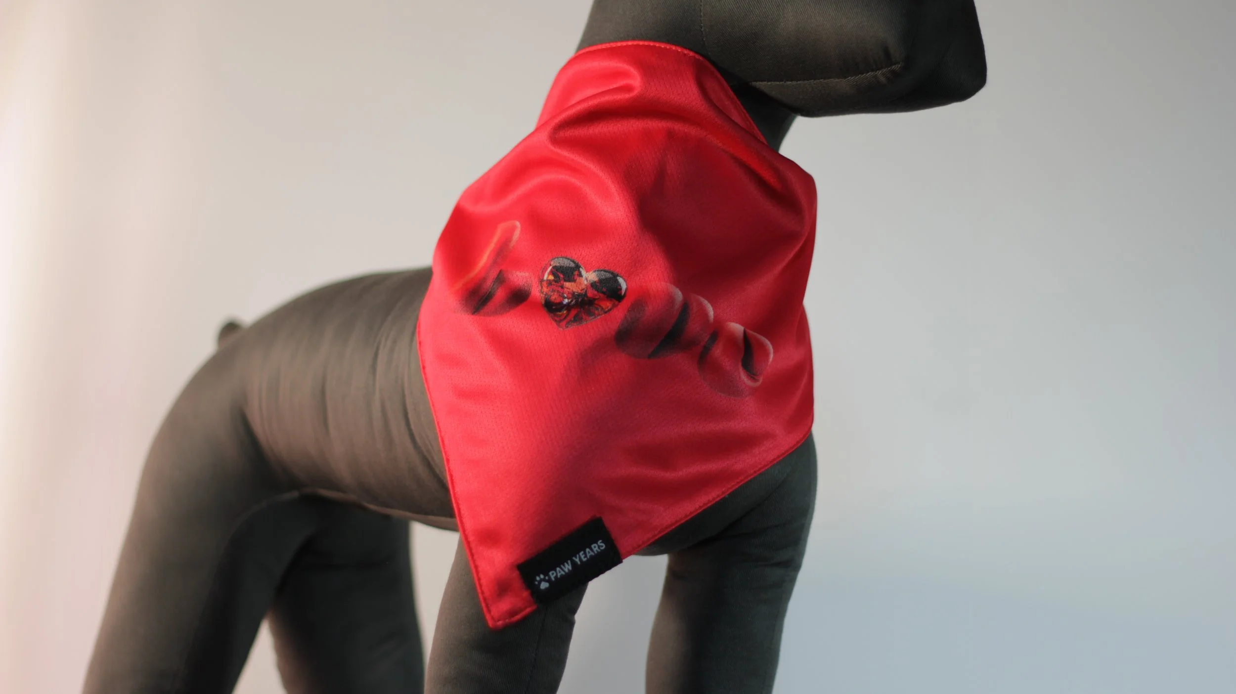 Small dog mannequin wearing the red side of the Winter Love reversible bandana featuring gem heart graphic.