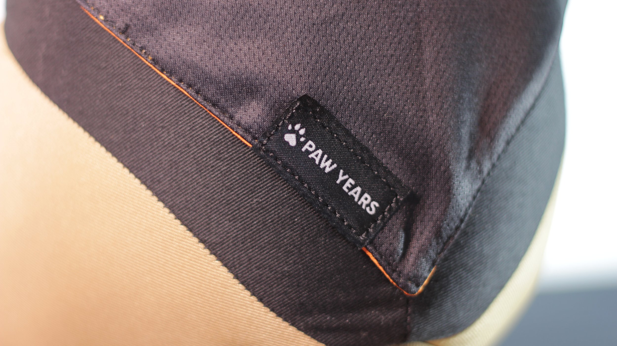 Macro detail of woven Paw Years logo tag on black mesh fabric.
