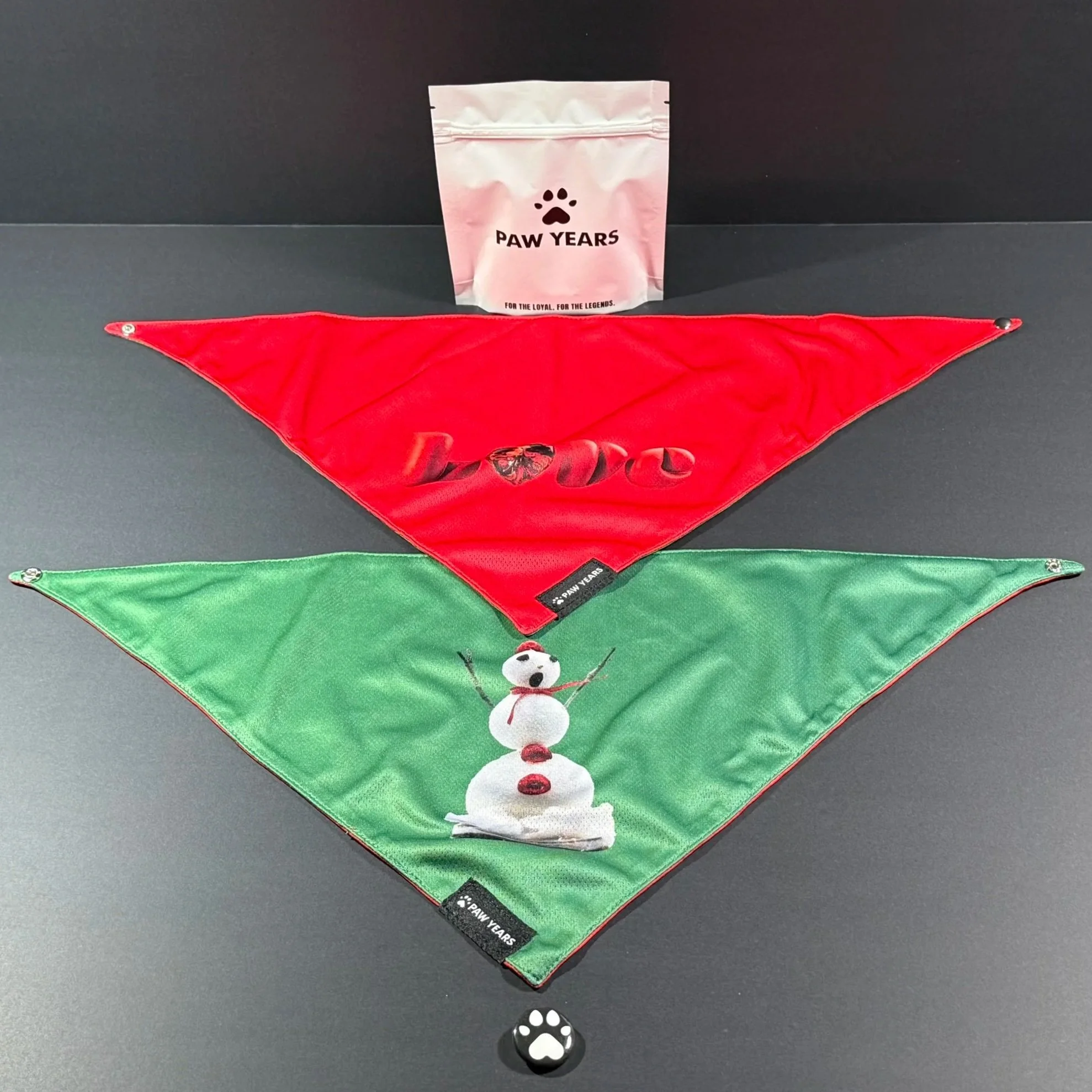Paw Years Winter Love limited edition reversible bandana set showing both green singing snowman and red ruby love heart designs with packaging.
