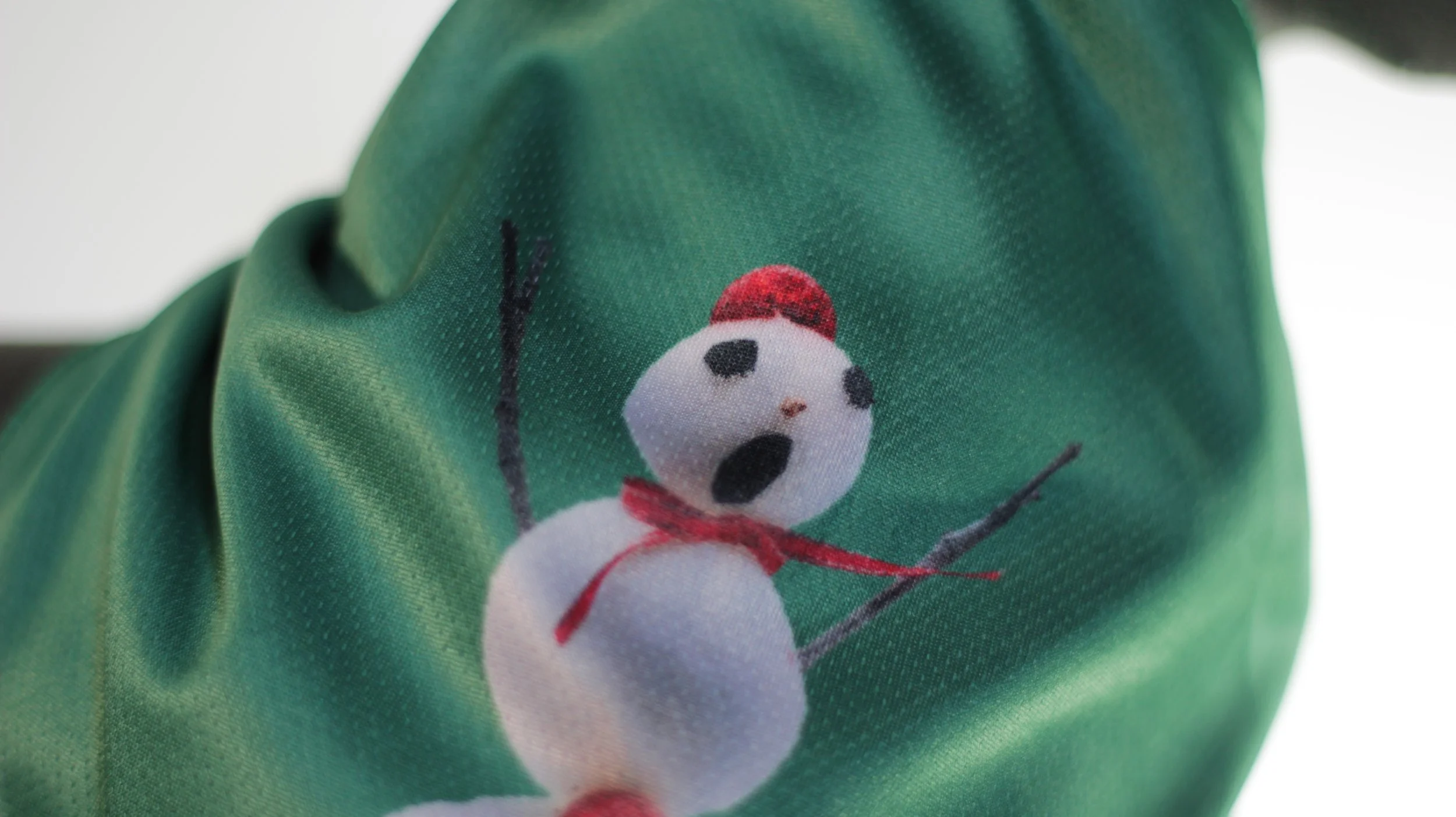 Detail shot of 3D style singing snowman face art on green winter dog bandana.
