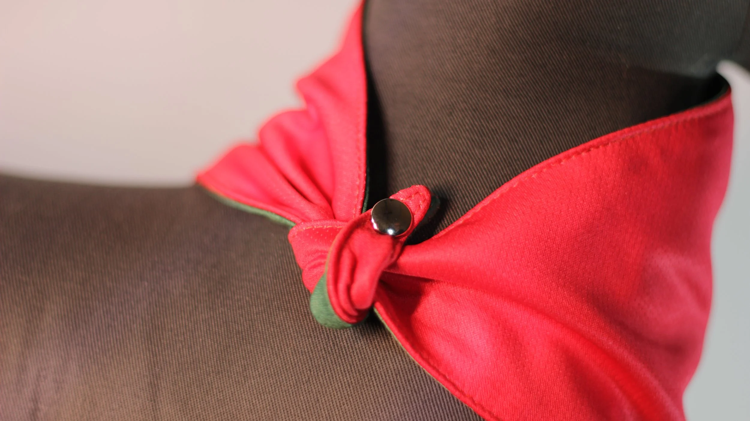 A close up of reinforced snap button closure on red and green reversible winter love bandana.