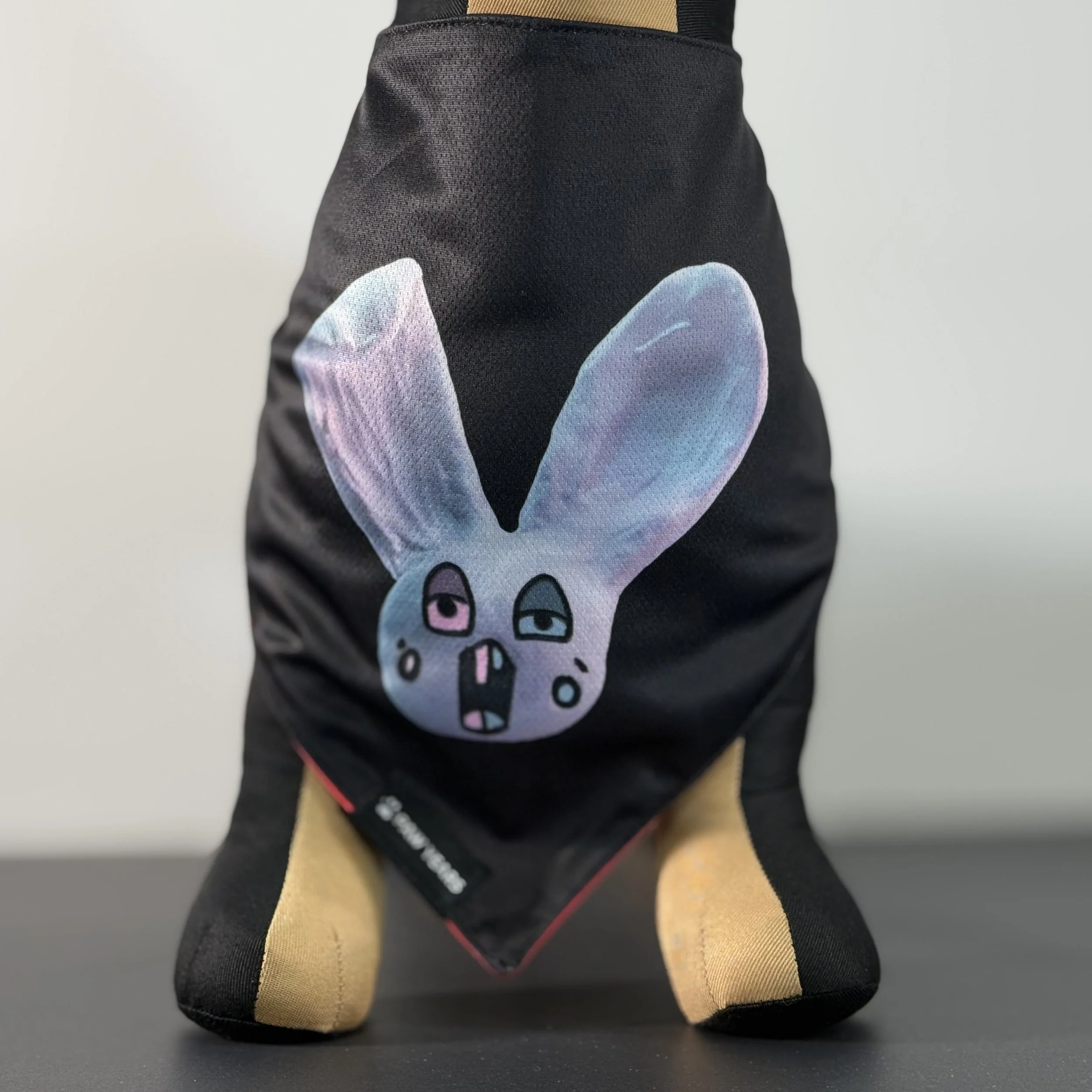 Front view of small dog mannequin wearing black Loopy bandana showing blue bunny art with pink and teal eyes.