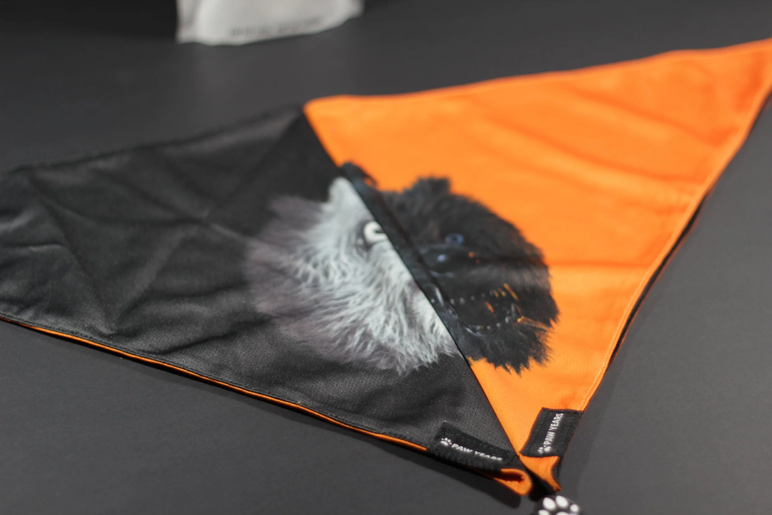 Detail shot showing reversible construction of Lycan werewolf bandana with both black and orange sides visible.