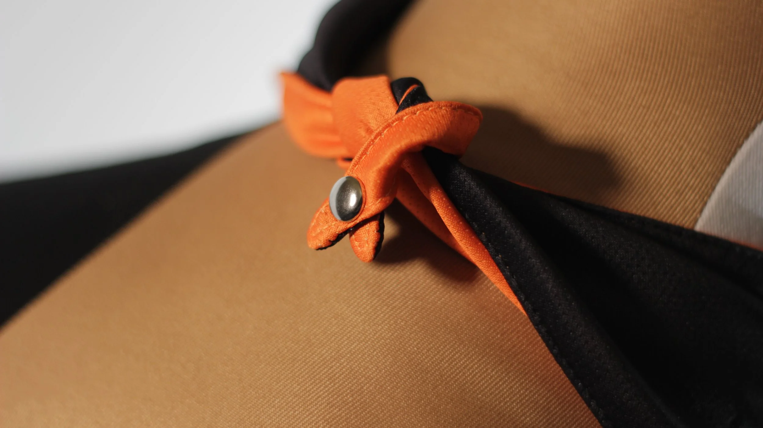 Macro close up of reinforced snap button closure on orange and black reversible Halloween bandana.