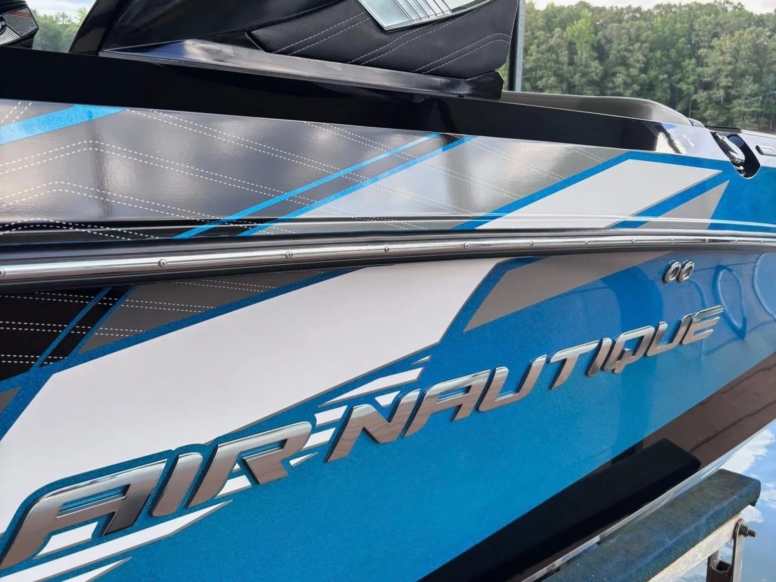 Close-up of a blue and white boat with the text 'Super Air Nautique' on the side, showing part of the boat's sleek design and metallic lettering.