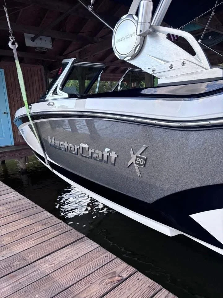 A MasterCraft X20 boat docked under a covered shed on a wooden dock.