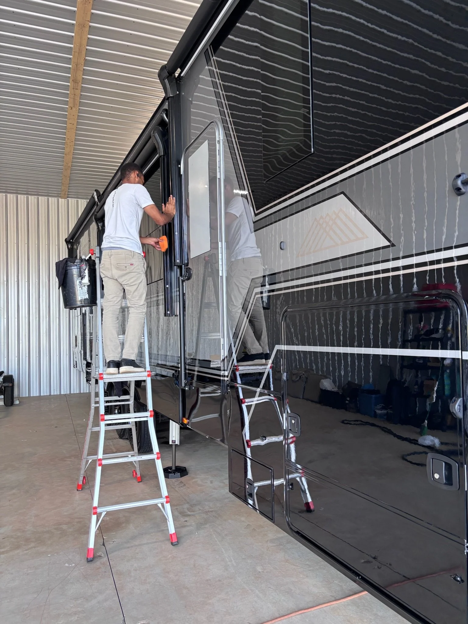 Close-up of a black Vintage car's hood ornament with a blurred sunset in the background.