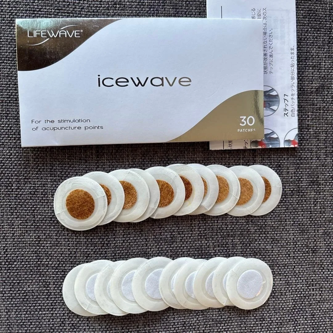 Box of 30 LifeWave IceWave acupuncture patches with two rows of patches placed below the box on a textured surface.
