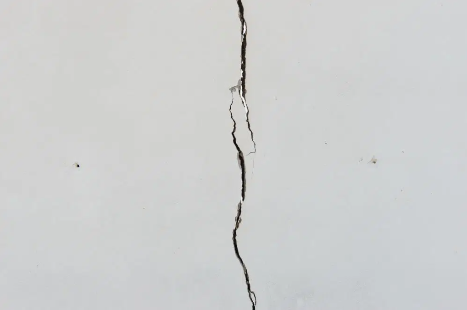 Close-up of a white wall with a long vertical crack.