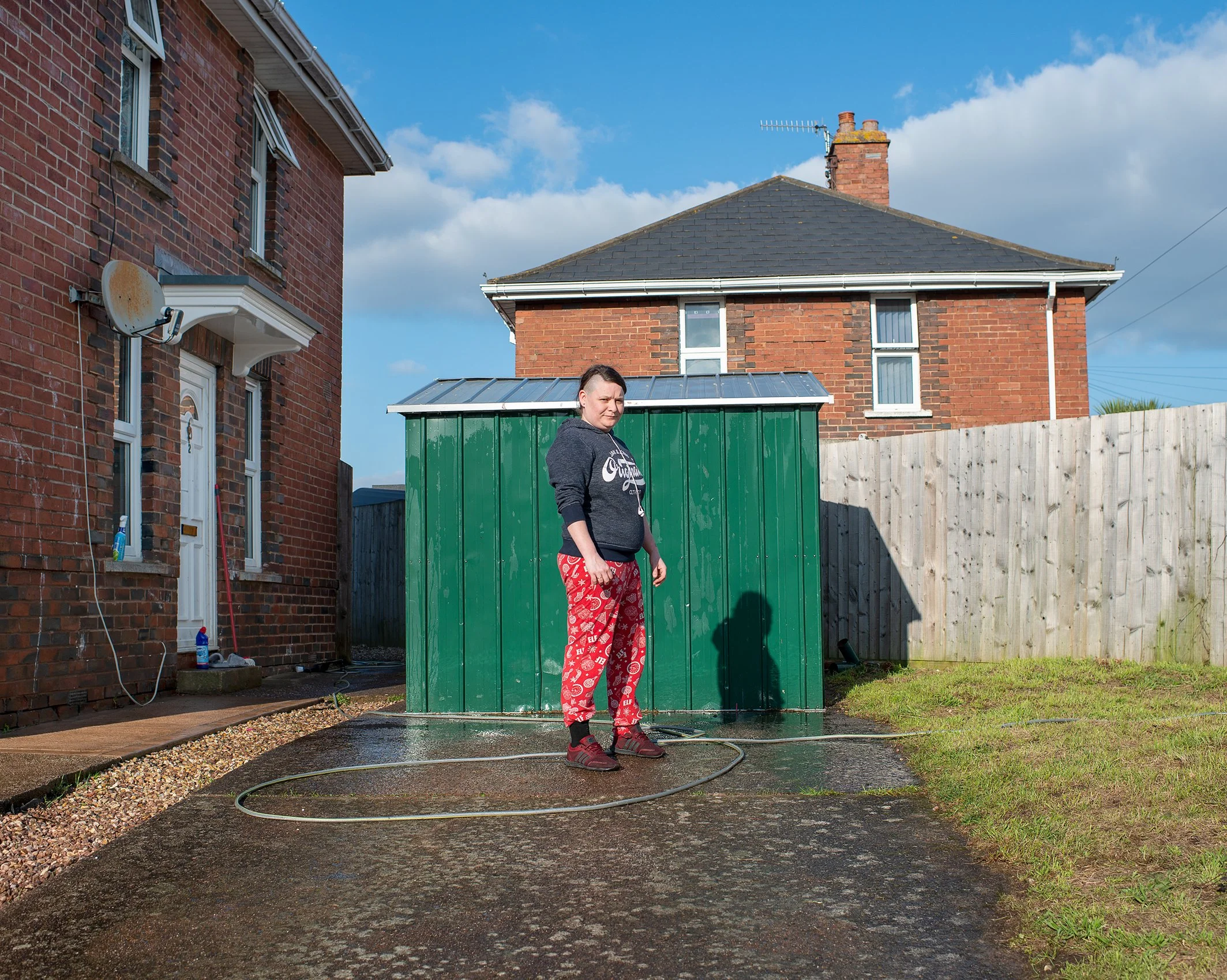 Woman with hosepipe in her front garden