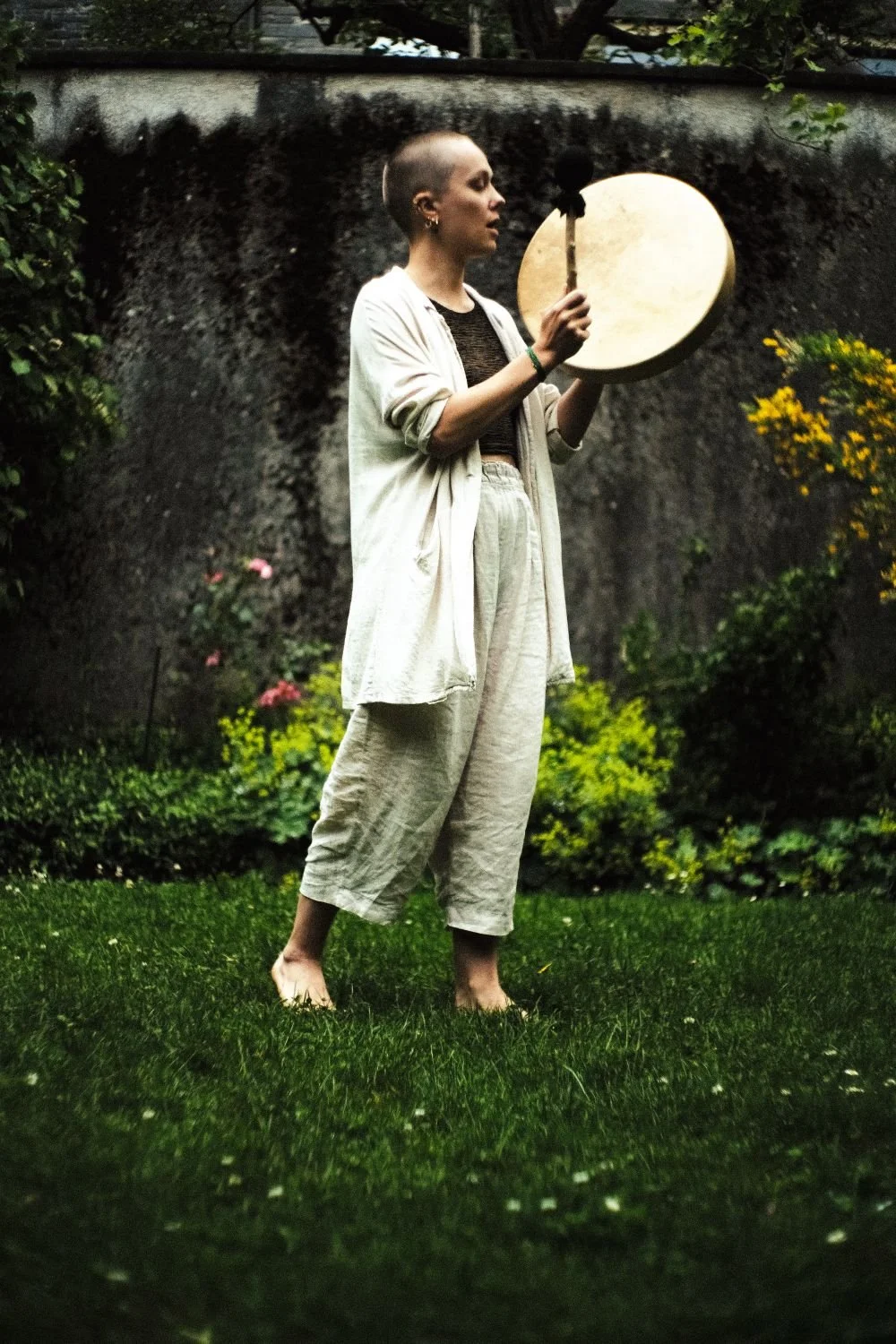 Katha Wirth mit Schamnischer Trommel am Singen und Jodeln im Garten. Katha leitet Klinging Circles, Naturjodel und Singkreise.