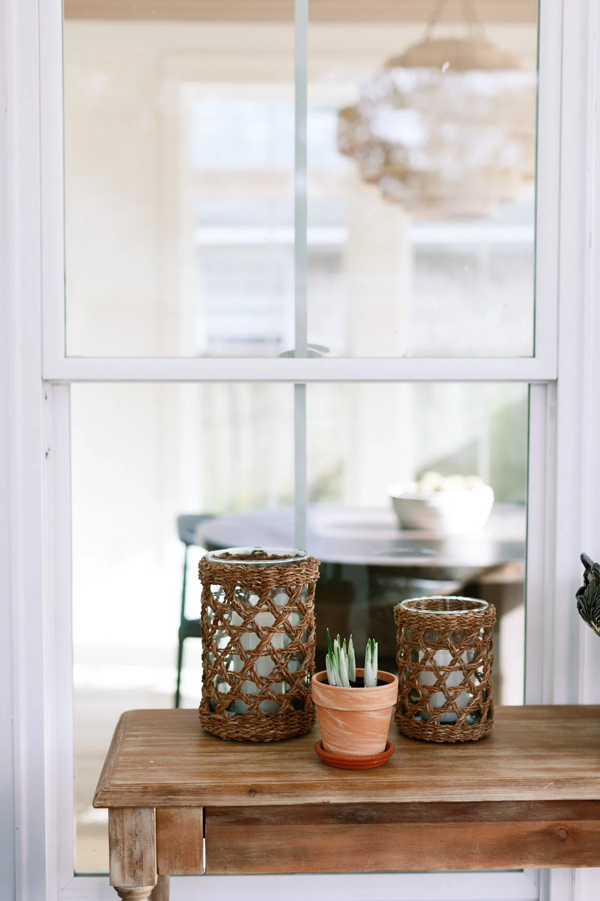 Cozy entryway table with woven lanterns and a summer hat.