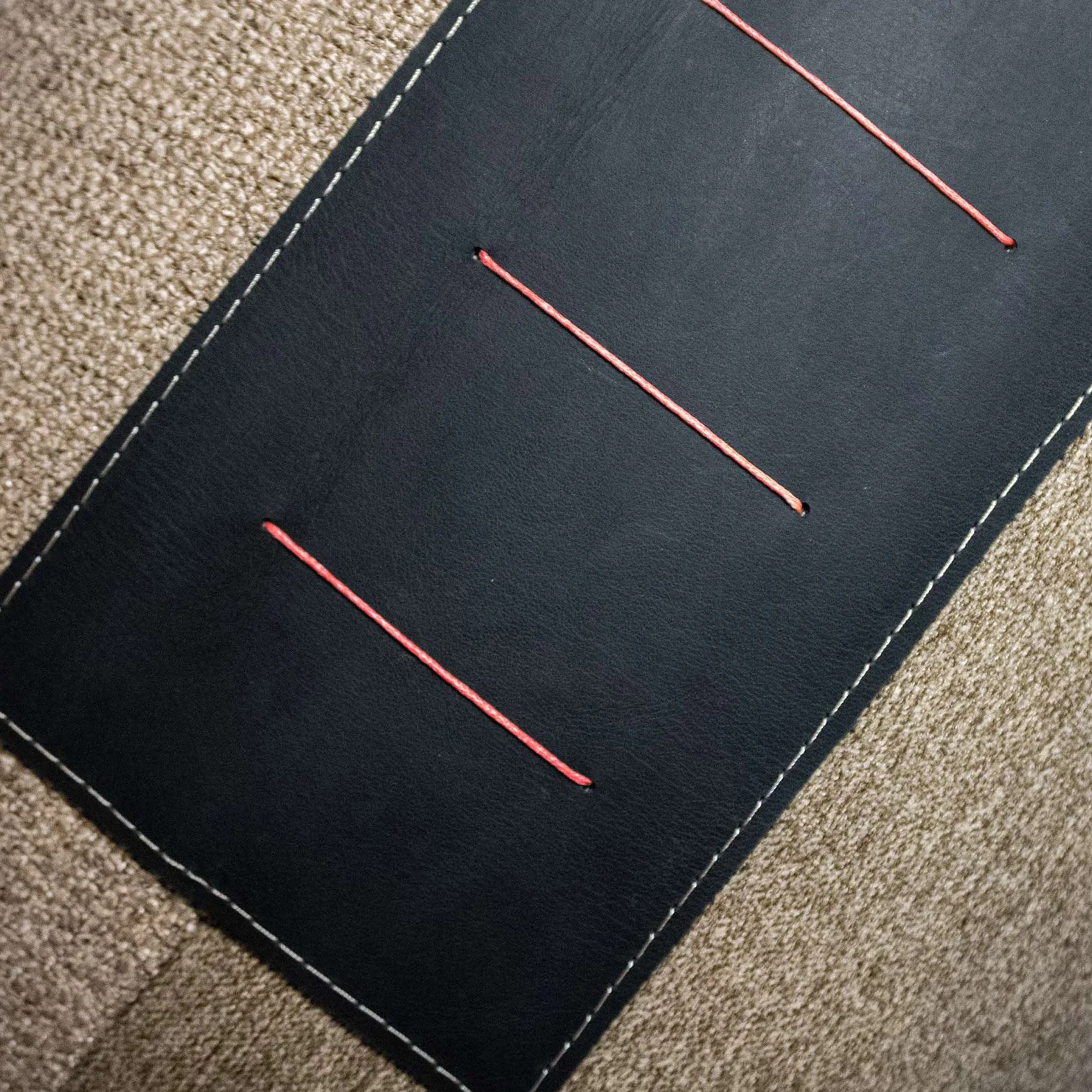 NASARA_01 decorative cushion in brown tonal textiles with black leather panel and vertical coral stitched detail