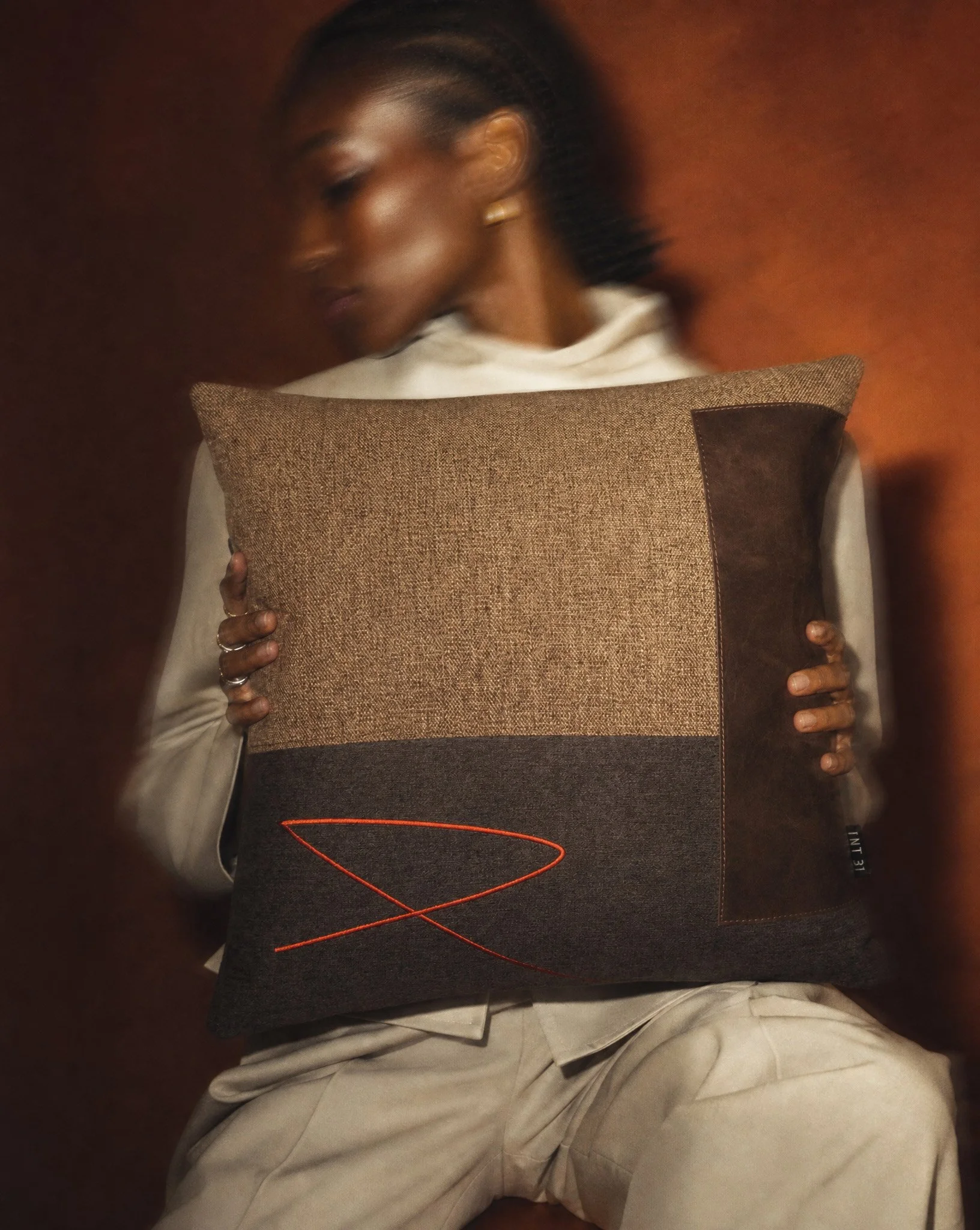 Generated-with-Kive.ai---female-model-with-dark-skin-lightly-holding-the-edges-of-a-20-x-20-inch-cushion-spanning-the-full-width-of-the-torso_-from-shoulder-to-shoulder.-Model-is-wearing-light-toned-monochrome-womenswear-with-architectu-(2).jpg