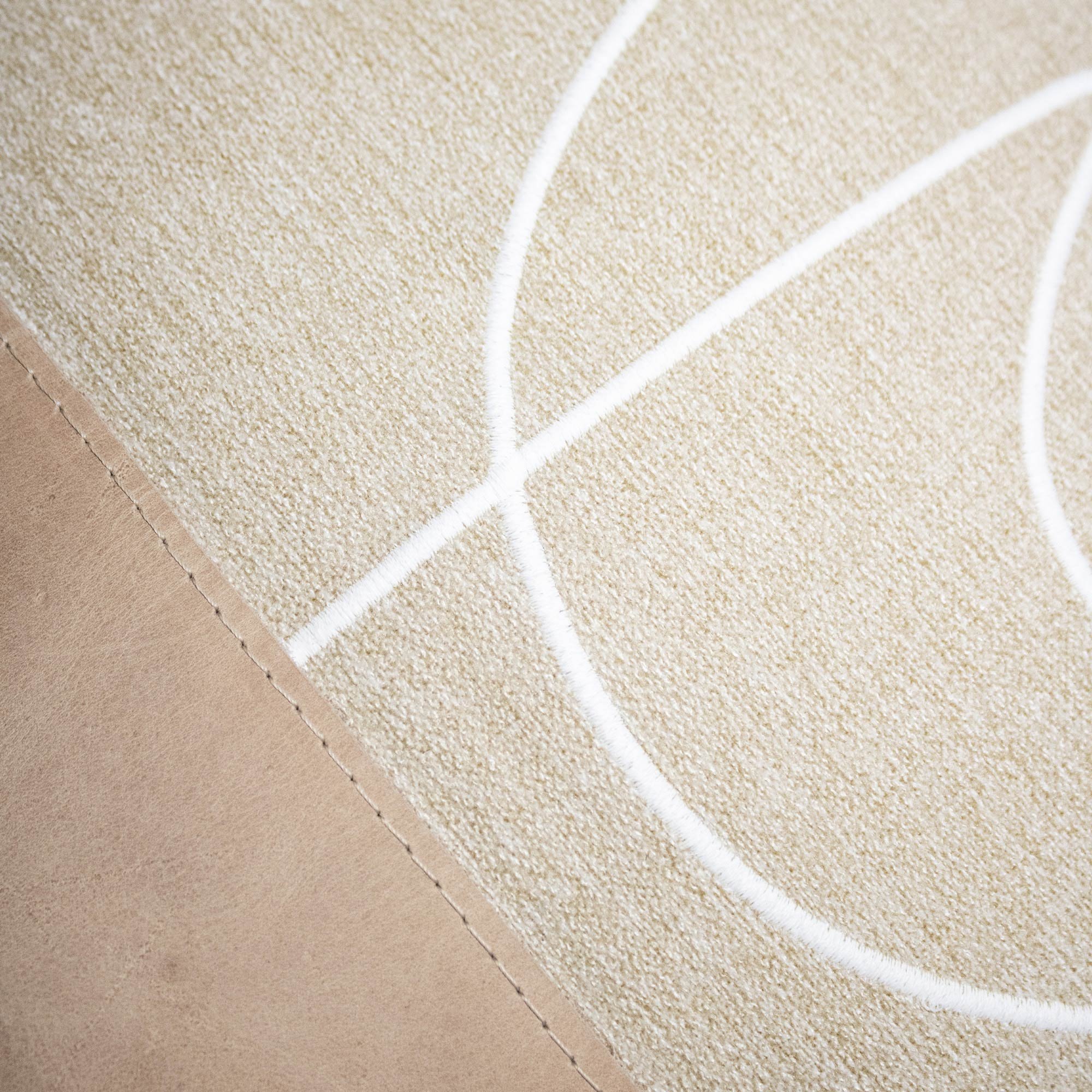 RAIO_02 decorative cushion in beige textile with tan leather panel and abstract white embroidered line detail