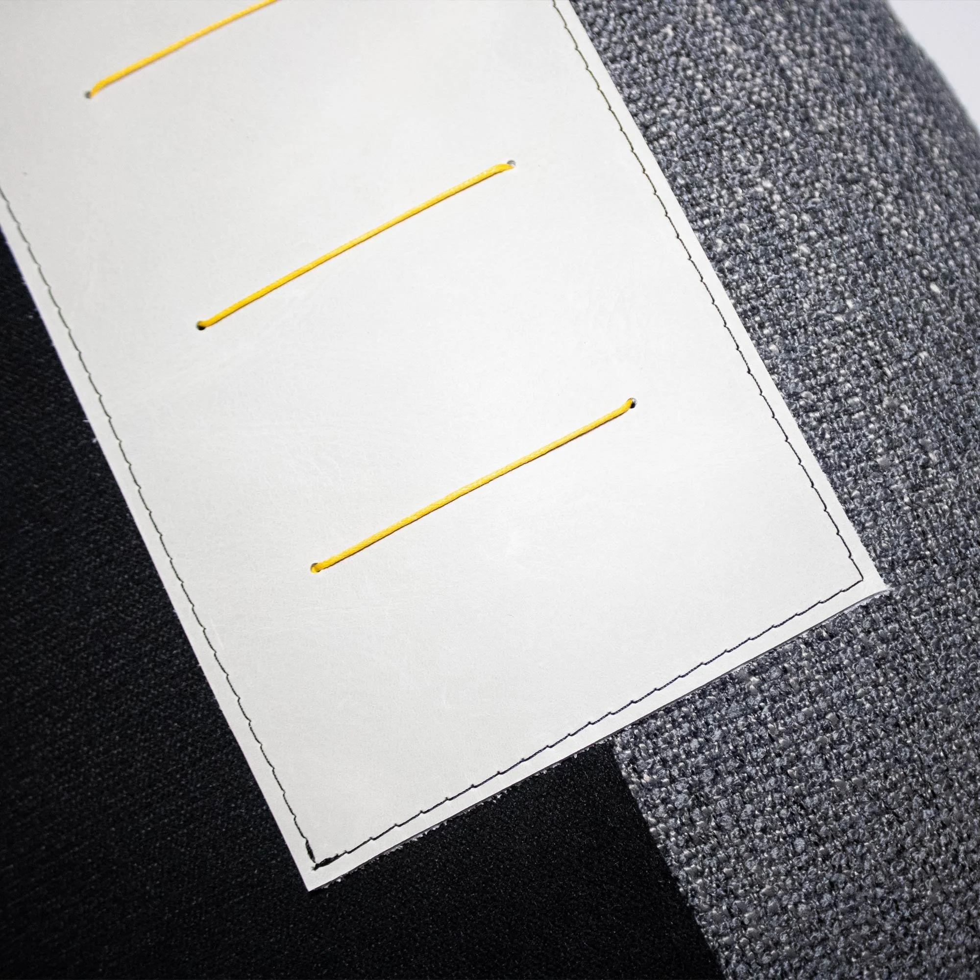 NASARA_02 decorative cushion in black and grey textile with light grey leather panel and vertical yellow stitched detail