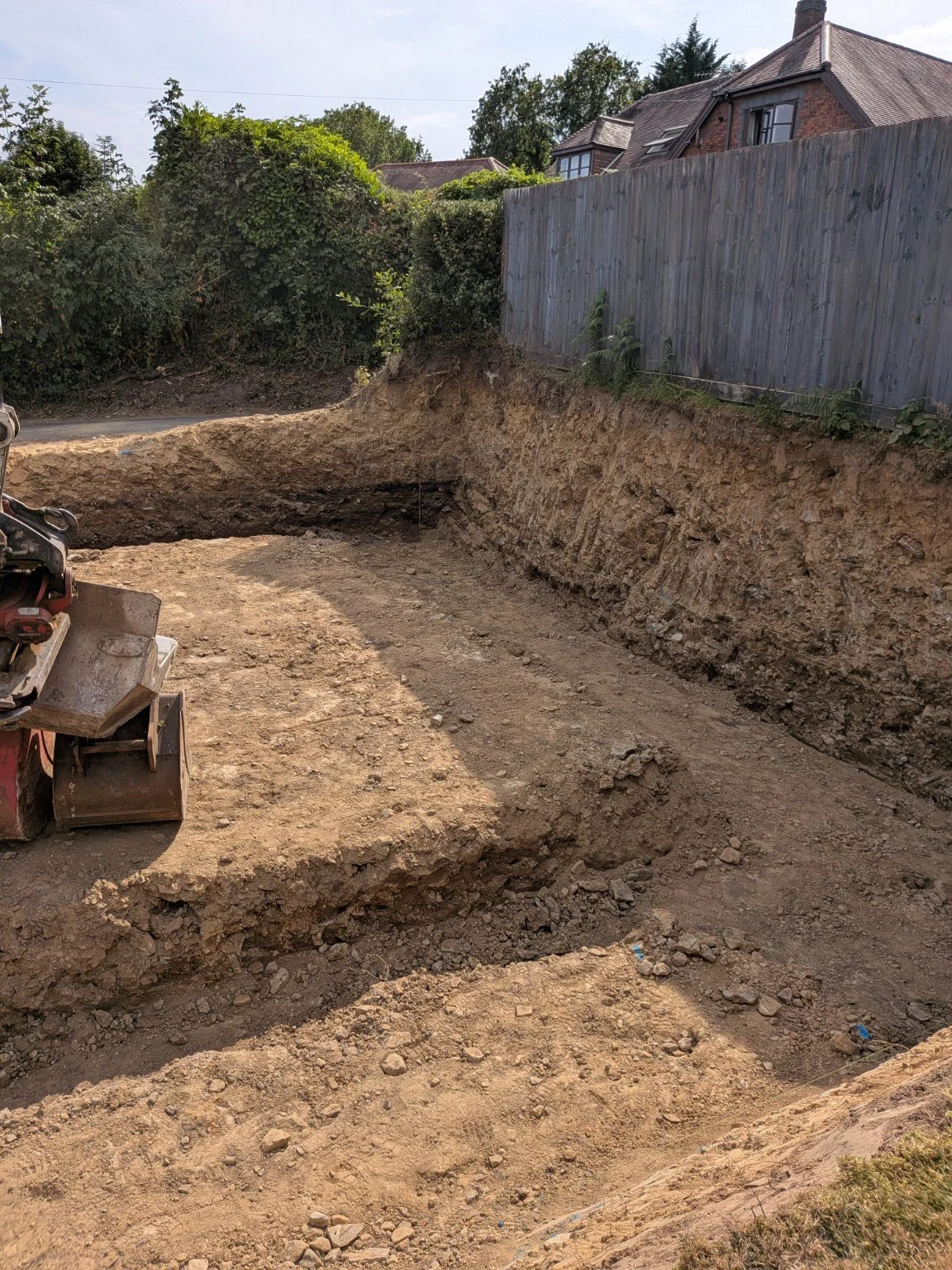 Excavated ground and foundation trenches beside a residential boundary fence
