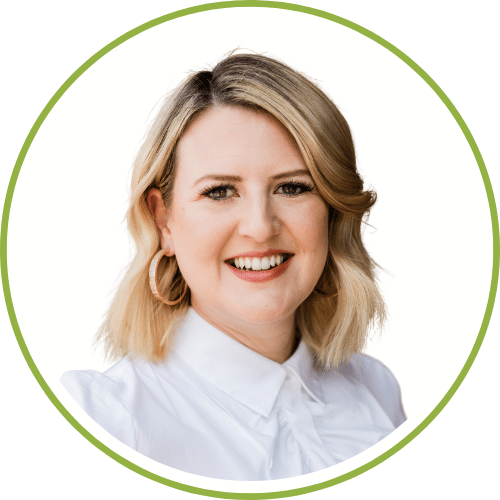 A woman with shoulder-length blonde hair, wearing a white collared shirt and earrings, smiling at the camera.