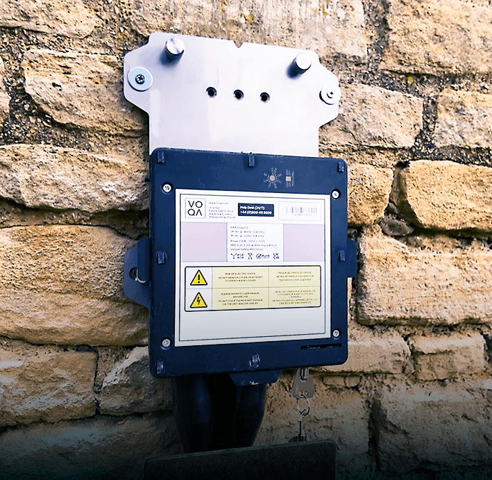 The Voqa One charging station 'cradle' back plate mounted on a brick wall