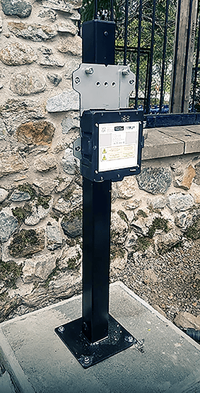 The Voqa One cradle fitted to a black pole on a concrete base in front of a stone wall