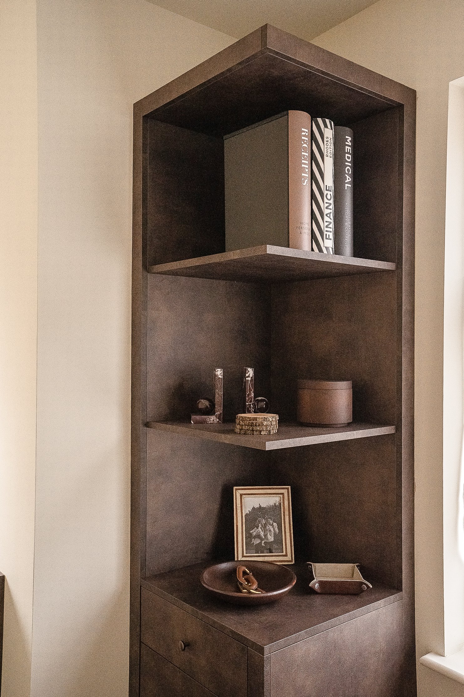Wooden shelf unit with books, decorative items, and framed photograph