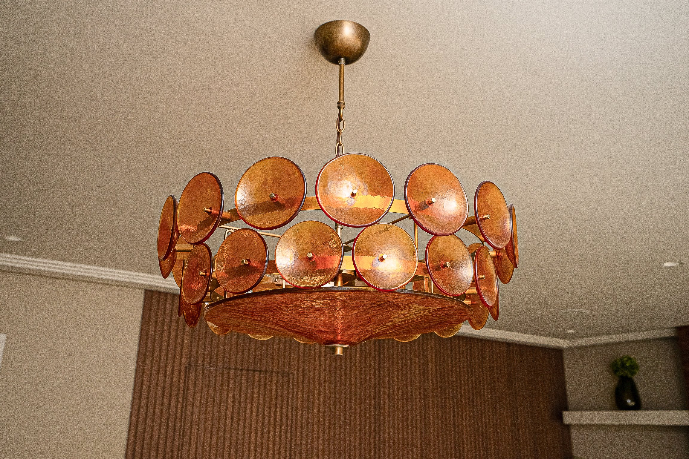 Modern chandelier with circular amber-coloured glass elements in a room with beige walls and ceiling.