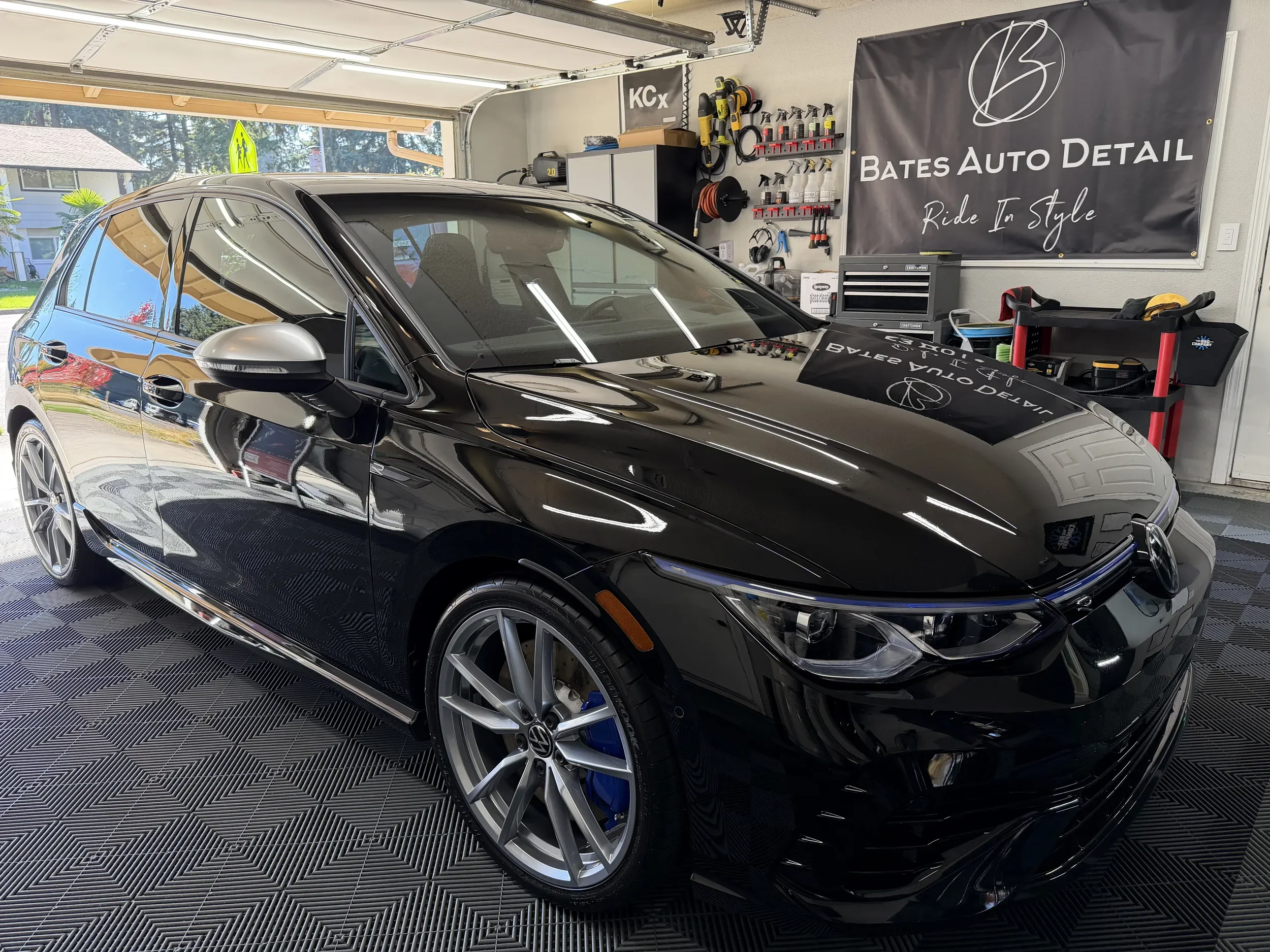 Polished black Volkswagen Golf in the Bates Auto Detail garage, shown from the front side.