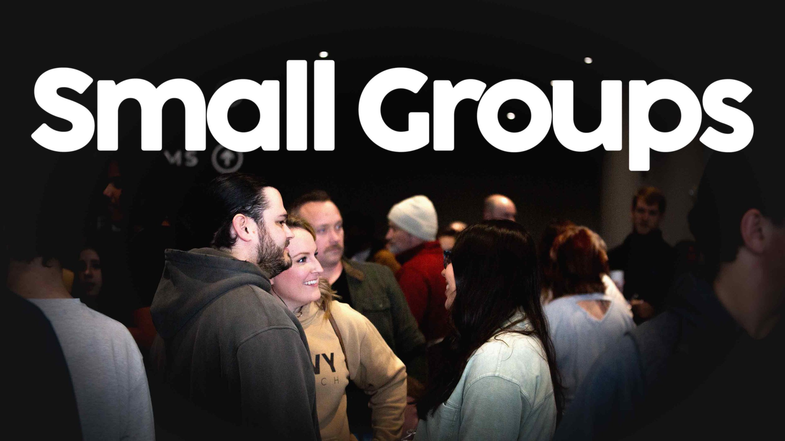 A group of diverse people in small groups having conversations at an indoor social event, with the words 'small Groups' prominently displayed at the top.