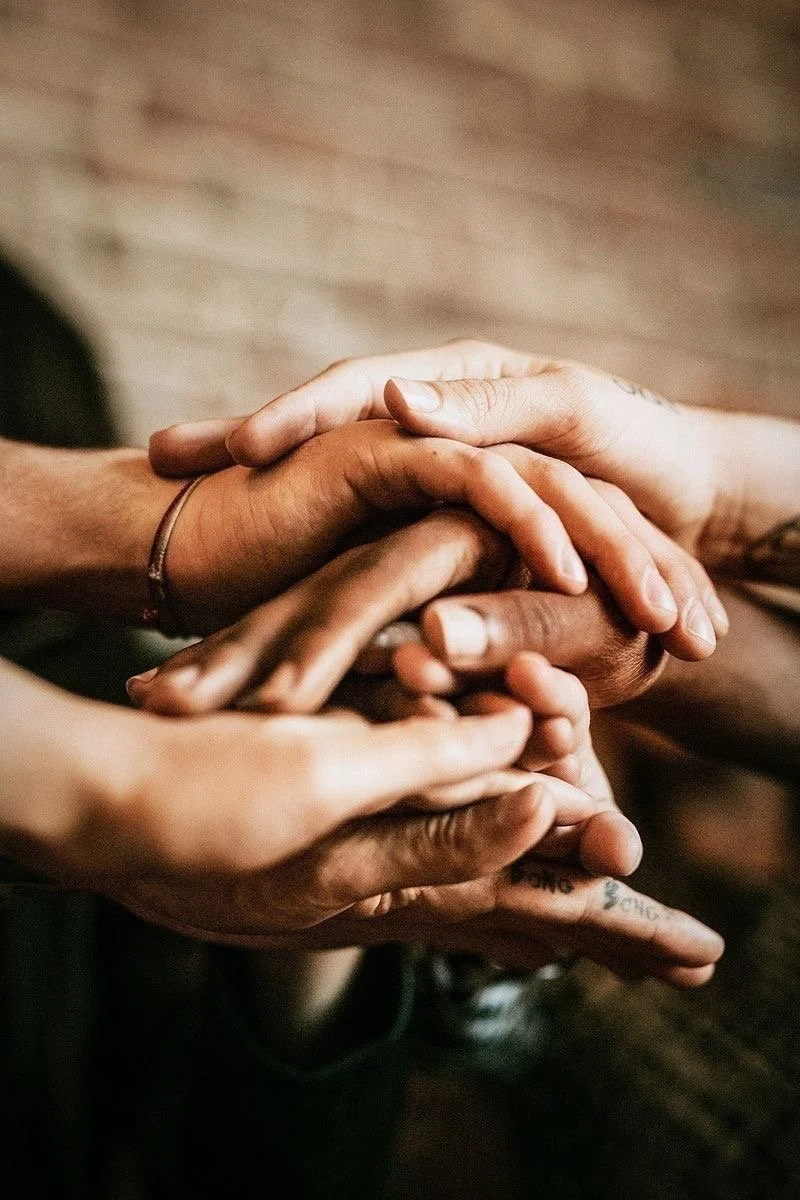 Multiple hands of different skin tones stacked together in a show of unity or solidarity.