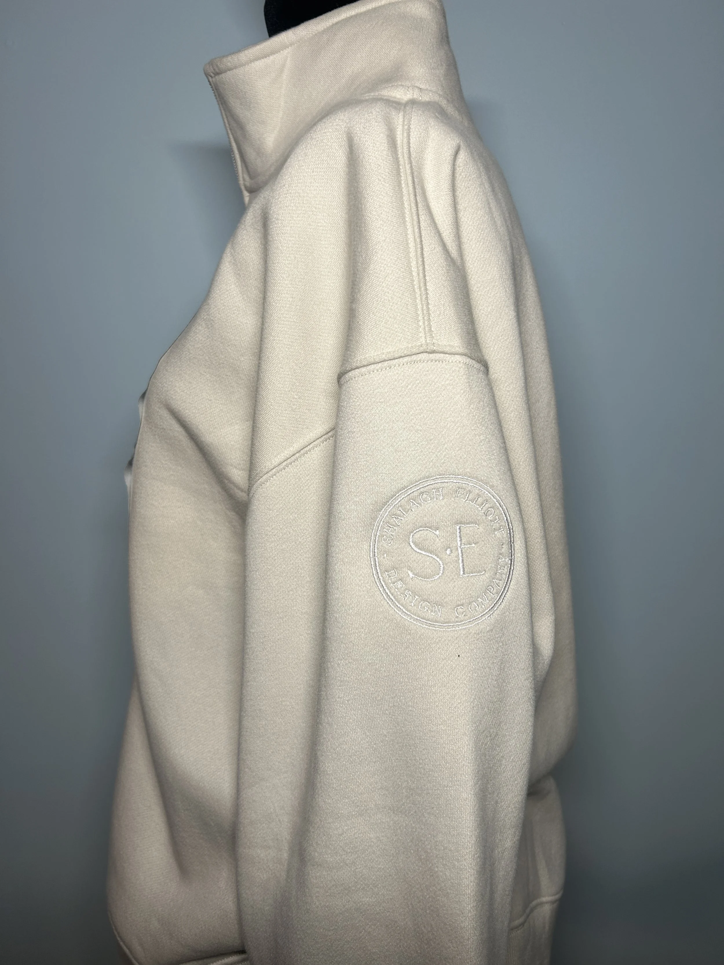 A white crewneck sweatshirt with a circular logo patch on the left sleeve that reads "SE Shawleigh Flight Design Company."