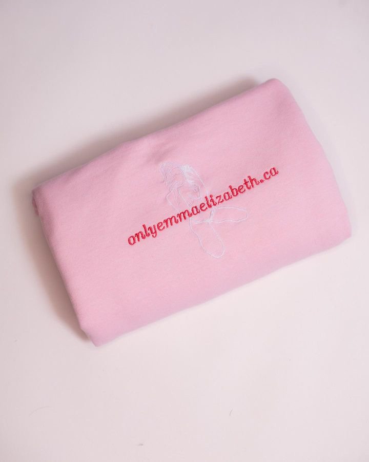 Pink fabric item with embroidered white butterfly and red text that reads 'onlyemmaelizabeth.ca'.
