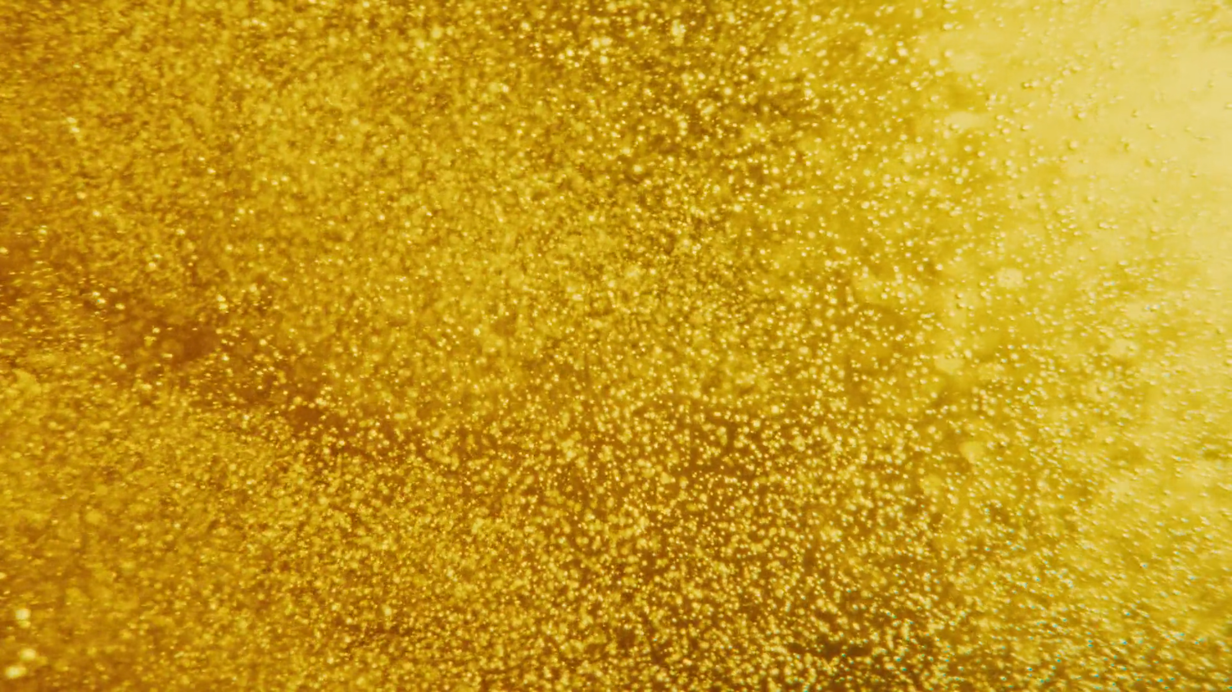Close-up of shimmering gold glitter surface with fine sparkling particles.