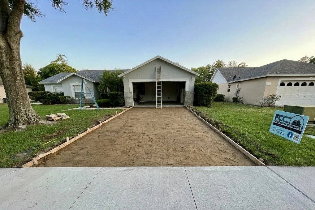 Freedom Concrete Construction yard sign and framed driveway sub-base prep in Davenport FL