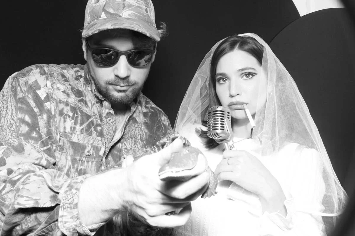 Creative couple Halloween costume Lana Del Ray and Alligator man pose for a photo booth picture.