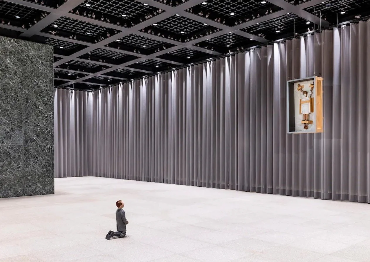 Maurizio Cattelan’s Him (2001), a kneeling figure viewed from behind, installed in the exhibition NIGHT at the Neue Nationalgalerie in Berlin.