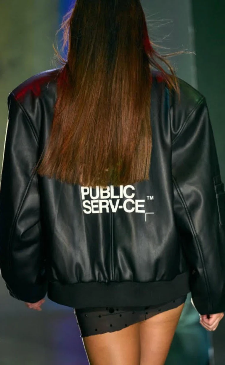 Model on the runway in Raphael Young's The Rest Is Noise SS27 collection for House of Public Serv-ce at New York Fashion Week bomber jacket with a logo on the back